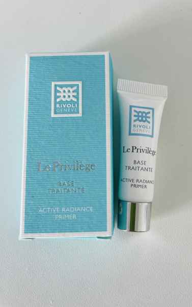 Eine blaue Schachtel und eine Tube Rivoli Genève Le Privilège Base Traitante Active Radiance Primer auf weißem Hintergrund.