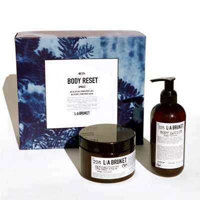 LA Bruket Body Reset Set mit Body Scrub und Body Lotion vor einer blauen Verpackung.